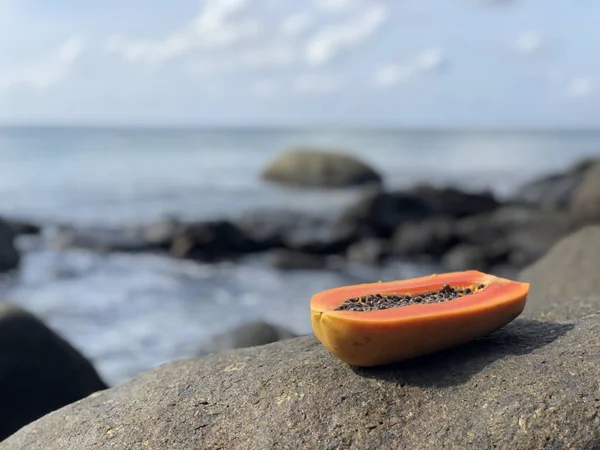 Mamão tailandês fresco suculento em uma pedra contra o mar e céu azul nublado à tarde — Fotografia de Stock