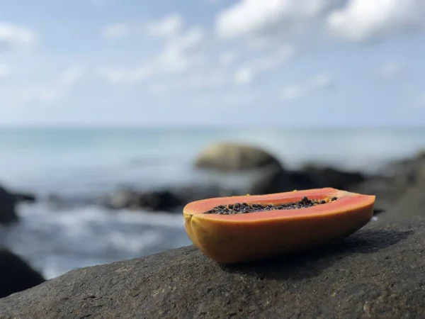 Mamão tailandês fresco suculento em uma pedra contra o mar e céu azul nublado à tarde — Fotografia de Stock