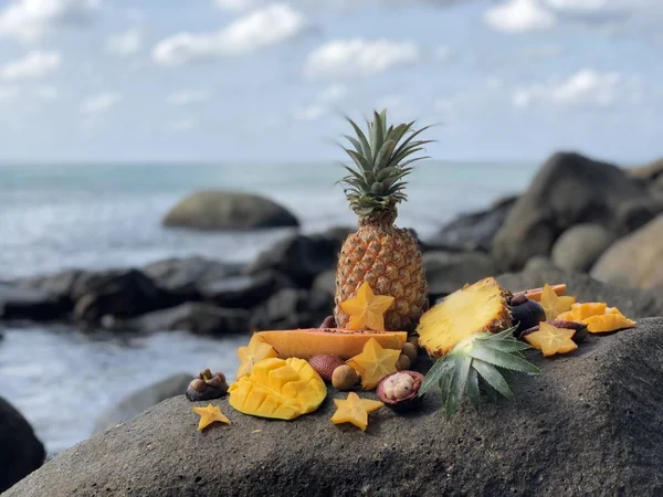 Manga de fruto tailandesa fresca suculenta, abacaxi, mangostão, mamão em uma pedra contra o mar e céu azul nublado de tarde — Fotografia de Stock