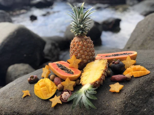 Saftige frische thailändische Früchte Mango, Ananas, Mangostan, Papaya auf einem Stein gegen das Meer und bewölkten blauen Himmel am Nachmittag — Stockfoto