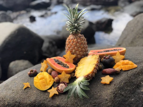 ジューシーな新鮮なタイの果物マンゴー、パイナップル、マンゴスチン、パパイヤ海と曇り空と石の上午後 — ストック写真