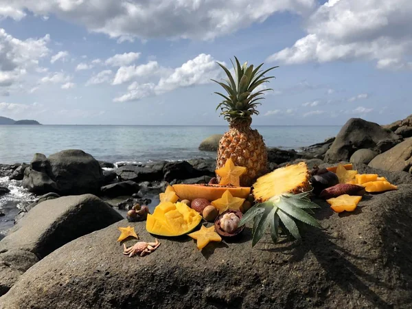 Manga de fruto tailandesa fresca suculenta, abacaxi, mangostão, mamão em uma pedra contra o mar e céu azul nublado de tarde — Fotografia de Stock