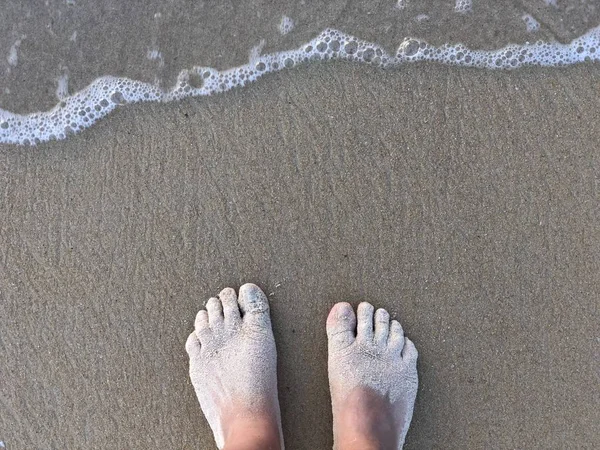 Женские ноги стоят на специальном поющем серебряном песке и на побережье пляжа Карон в Пхукете Таиланд на закате — стоковое фото