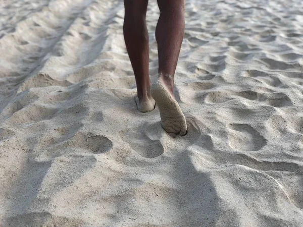 Мужские загорелые ноги в белом мелком песке уникального пляжа Карон Пхукета на фоне моря и Золотого заката, ощущение удовольствия и гармонии — стоковое фото