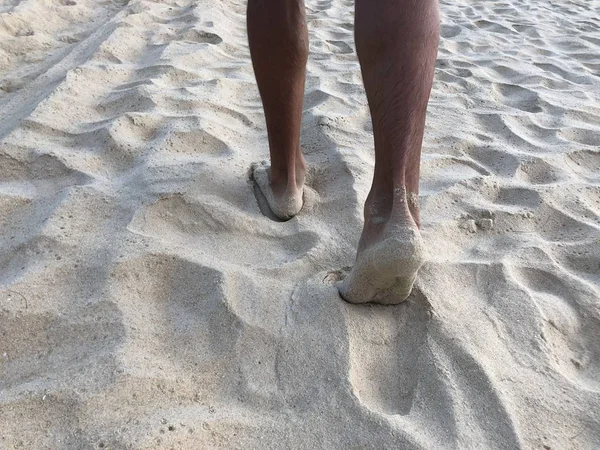Мужские загорелые ноги в белом мелком песке уникального пляжа Карон Пхукета на фоне моря и Золотого заката, ощущение удовольствия и гармонии — стоковое фото