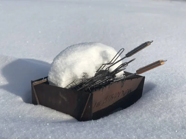 Grelha e churrasqueira cobertos de neve em um dia ensolarado de inverno — Fotografia de Stock