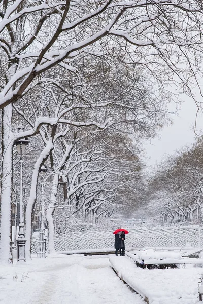 Paris under the snow, the boulevard Richard-Lenoir with two people under a red umbrella