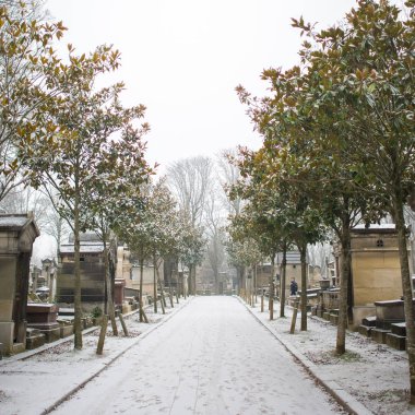 Pere Lachaise Mezarlığı, mezarlık mezar taşları, kış aylarında kar ve ağaçları ile kaplı patika yol, 