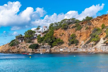 Ibiza, Sa Caleta plaj, eski fishermans tutuyor kıyı ve modern evler, güzel kırmızı kayalıklarla 