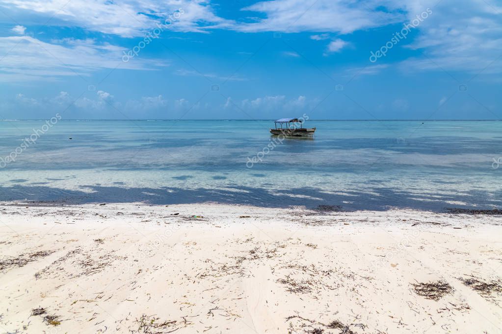 Zanzibar in Tanzania, beautiful beach with white sand, and a typical fishing boat