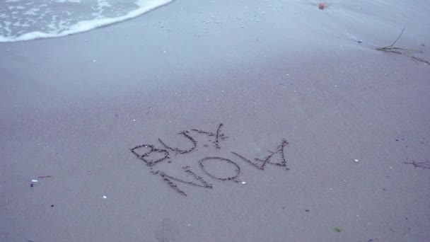 Escrito "Compre Ahora" en la arena del mar — Vídeo de stock