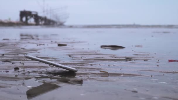 Смартфон падает на землю на мокром пляже — стоковое видео