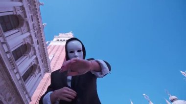 Maskeli adam Venedik 'in arka planında dans ediyor.