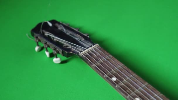 Yeşil zeminde kırık bir teli olan eski bir gitar. — Stok video
