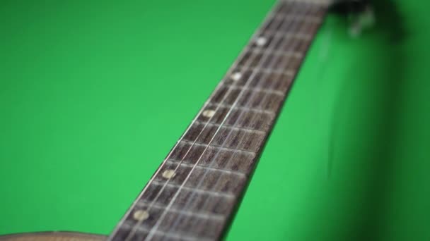 En gammal gitarr med brutet snöre på ett grönt golv — Stockvideo