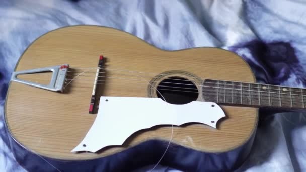 Guitarra con cuerda rota apoyada en la cama — Vídeo de stock