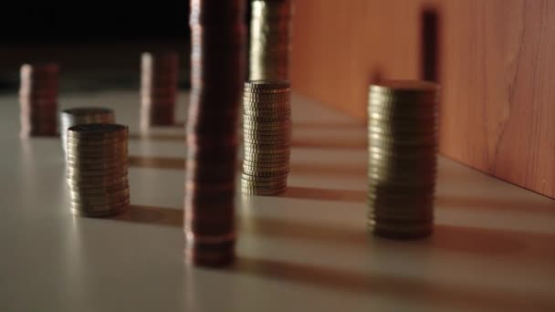 Monedas colocadas en grupos sobre un mueble e iluminadas por una luz — Vídeo de stock