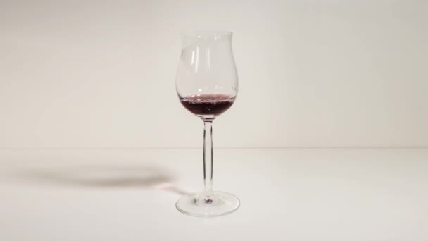 En glasbägare är fylld med rött vin — Stockvideo