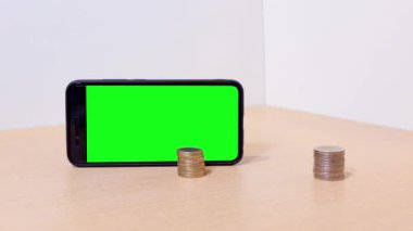 Önünde bozuk paralar olan yeşil ekranlı akıllı telefon.
