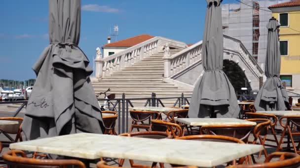 Mesas y sillas de restaurante al aire libre con puente veneciano detrás — Vídeos de Stock