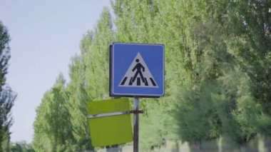 Arkasında ağaçlar olan yaya geçidi tabelası