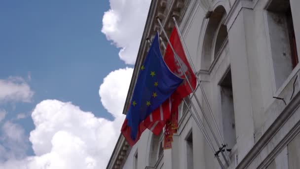 Evropská vlajka s dalšími vlajkami vzadu na fasádě budovy — Stock video