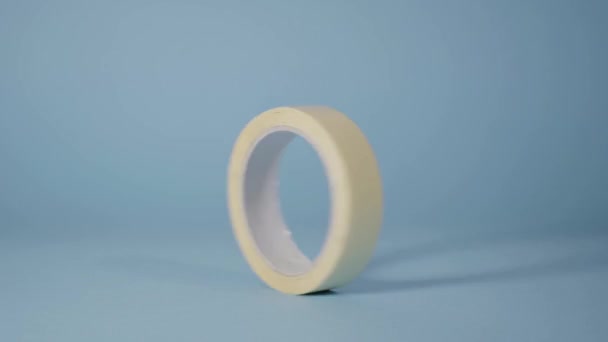 Witte scotch roll draait en stopt op een blauwe achtergrond — Stockvideo