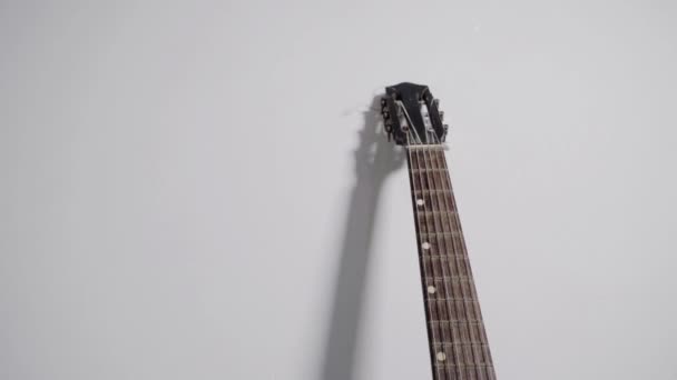 Guitarra apoiada na parede branca — Vídeo de Stock