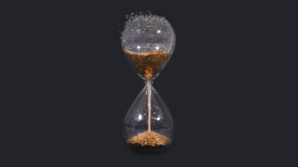 Hourglass disintegrates into pieces on a black background — Stock Video