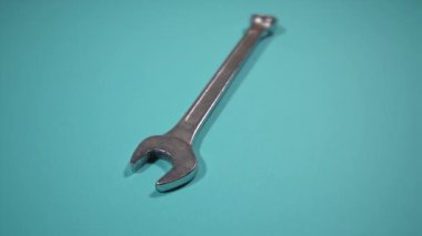 Turkuaz arka planda parlayan ingiliz anahtarının arkasındaki hareket