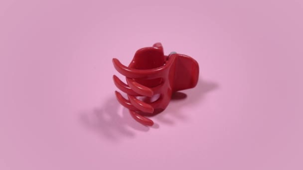 Movimento intorno clip artiglio bambino di plastica rossa su sfondo rosa — Video Stock