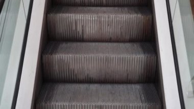 Aydınlık salonda cam kenarlı yürüyen merdiven yükselmeye başlar.