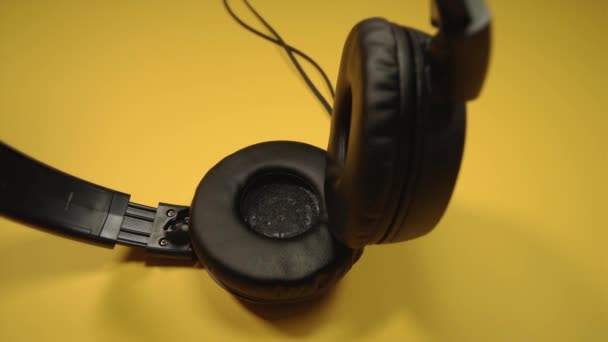 Zeitgenössische schwarze Kopfhörer mit Kordel auf gelbem Hintergrund — Stockvideo