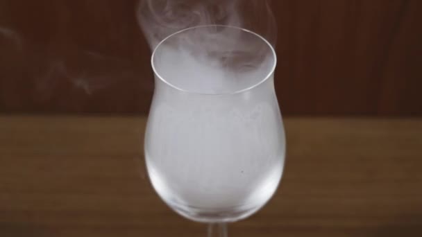 Fumo bianco scorre all'interno moderno bicchiere da vino di lusso su marrone — Video Stock