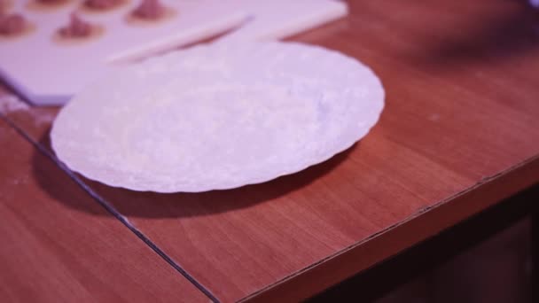 На тарелку с мукой кладут сырую пельмень ручной работы — стоковое видео