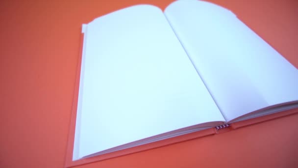 Livre ouvert avec des pages vides sur fond orange — Video