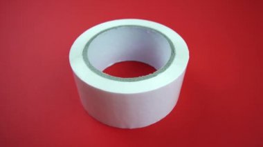 Kamera kırmızı arkaplanda yapıştırıcı bant etrafında sola döner