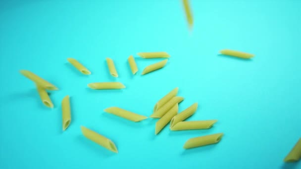 Penne secche pezzi di pasta cadere su sfondo azzurro — Video Stock