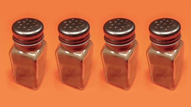 Peppar shakers full av krydda slå på orange bakgrund — Stockvideo