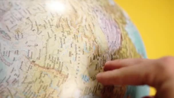 homme marche le long du globe tournant par les doigts contre jaune