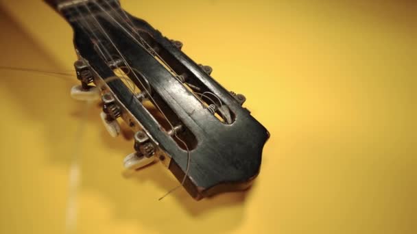 Mouvement autour de la vieille tête de guitare en bois noir sur jaune — Video