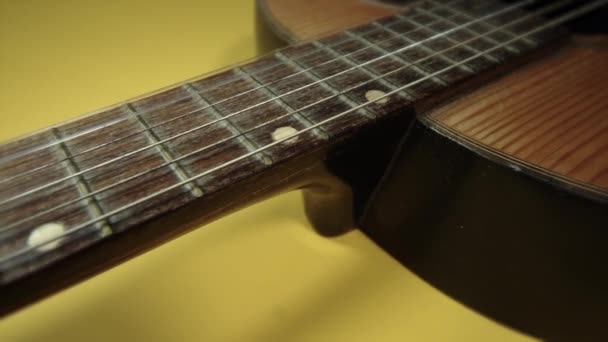 Movimiento a lo largo de cuello de guitarra de madera vintage en amarillo brillante — Vídeo de stock