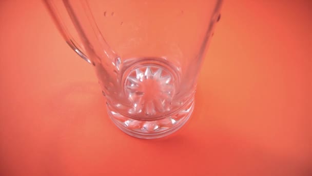 Derramando cerveja fresca em caneca de vidro no fundo laranja — Vídeo de Stock