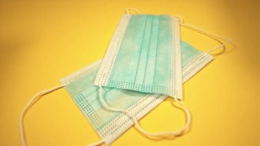 Yeni cerrahi maskeler sarı yüzeye yakın planda düşer.