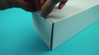 Adam turkuazda uçan dumanla dolu karton kutuyu açıyor.