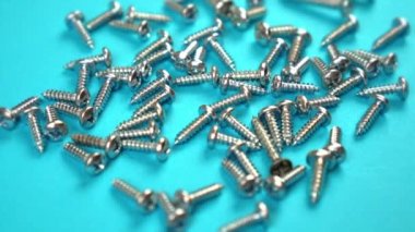 Yeni parlak gümüş vidalar açık mavi arkaplanda yatıyor.