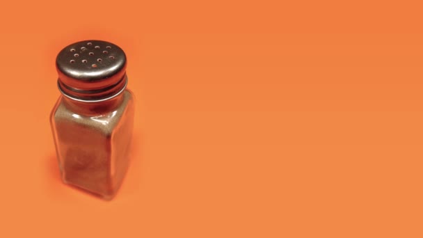 Saltador de pimenta cheio de condimentos gira em pano laranja brilhante — Vídeo de Stock