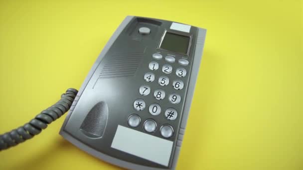 Persoon zet handset op grijze bekabelde telefoon op geel closeup — Stockvideo