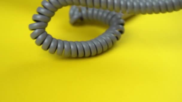 Grey spiral phone wire and handset falling down on yellow — Stock Video