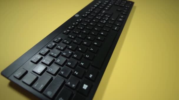 Беспроводная клавиатура на ярко-желтом фоне крупным планом — стоковое видео